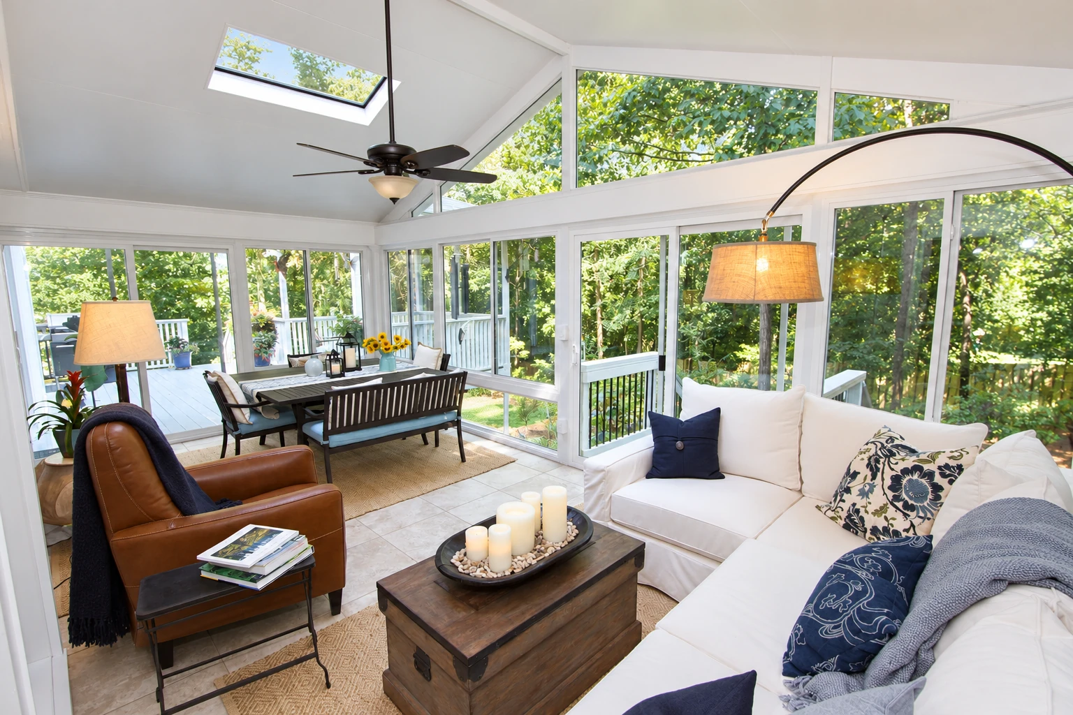 Bright sunroom converted from a deck, with white-framed windows, a skylight, dining area and cushioned seating.