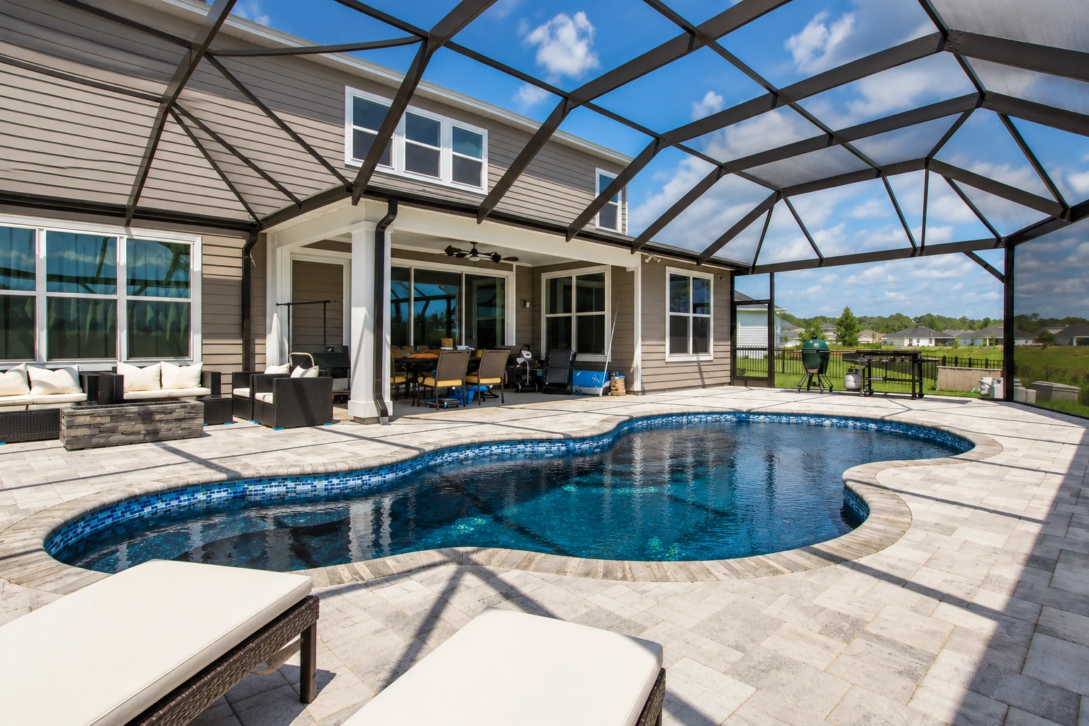 Screened patio enclosure with a dark metal frame surrounding a swimming pool and paved deck.